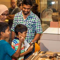 Drop-In: Stone Age Handling Workshop in the Learning Resource Room - a family looking at old artefacts on a table
