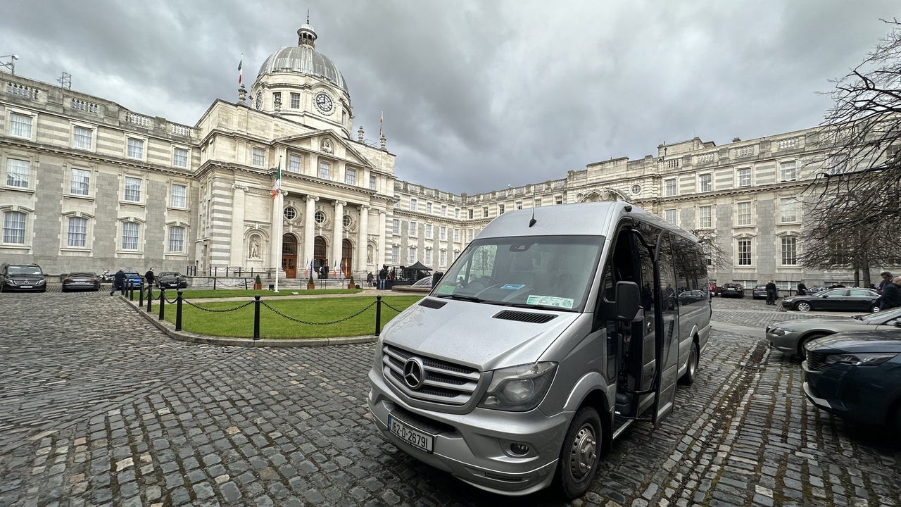 Silver minibus parked on a cobbled street in front of a large historic building