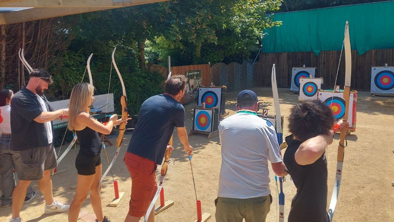 A group of people lined up in front of targets with bows in their hands