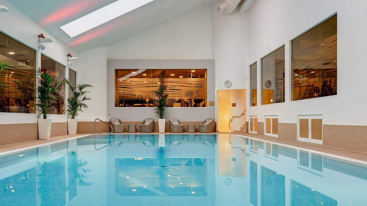 Swimming pool with wicker chairs and tables at the edge and plants