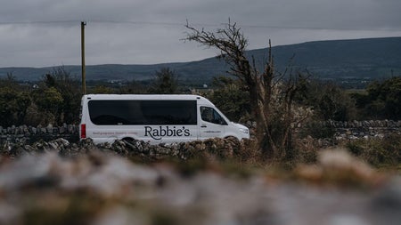 A small tour bus parked beside a country view