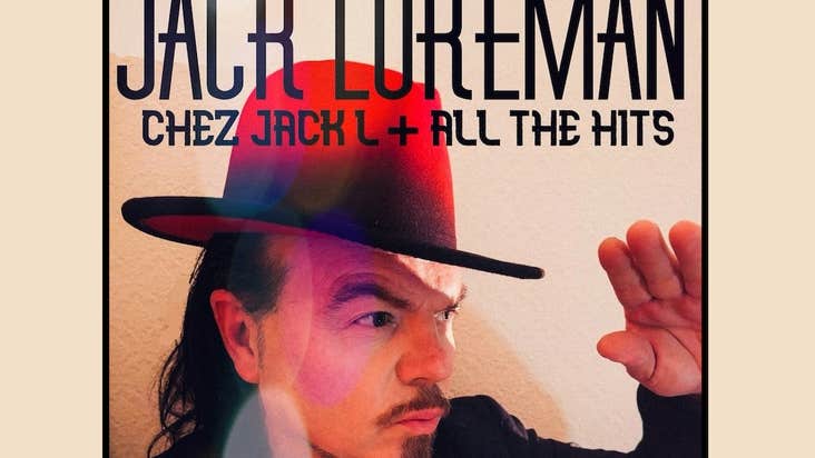 A man in large brimmed red hat is holding up one hand as sheltering from the sun