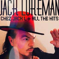 A man in large brimmed red hat is holding up one hand as sheltering from the sun