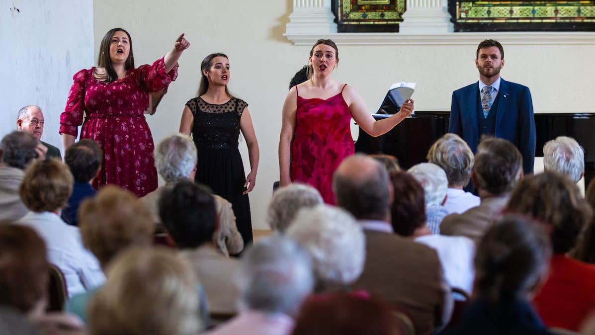 Chorus Recital 2022 in Villierstown church, 3 women and 1 man standing in front of an audience singing, one is pointing.