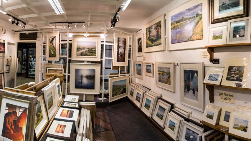 Interior of Jane Hilliard's gallery with framed paintings and prints lining the walls