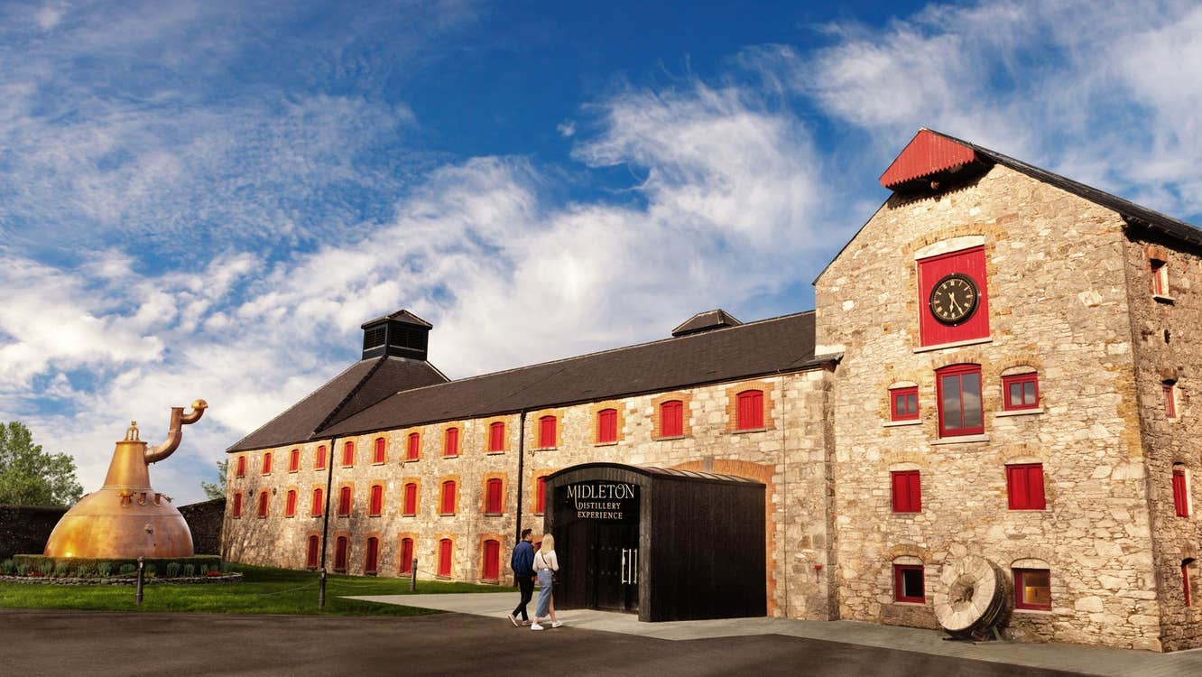 A large building with exterior walls of brick and a replica of a whiskey still outside