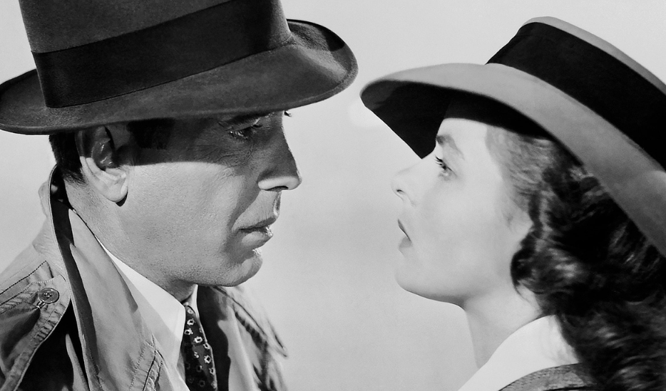 Head and shoulder shots from side profile of a man and woman facing each other, looking intently, both wearing hats