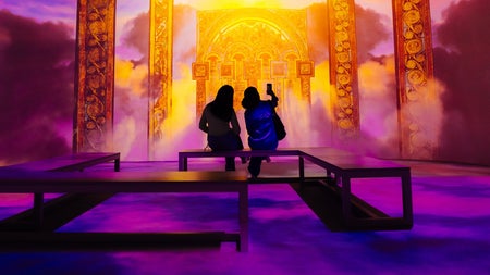 Two people enjoying The Book of Kells 360 experience which is a journey in light and sound