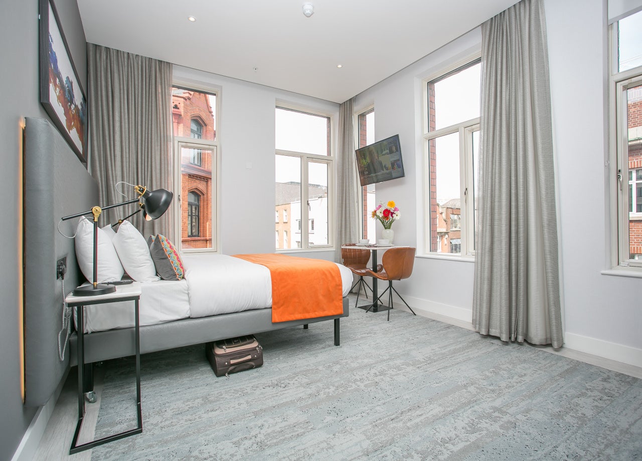 Double bedroom with white and orange sheets