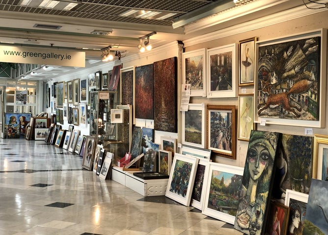 A room with walls full of framed artworks in various sizes