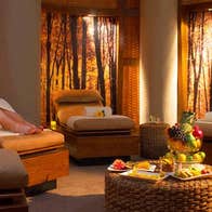 A lady in a bathrobe relaxing on a lounge in a softly lit room in the Escape Spa at the Imperial Hotel