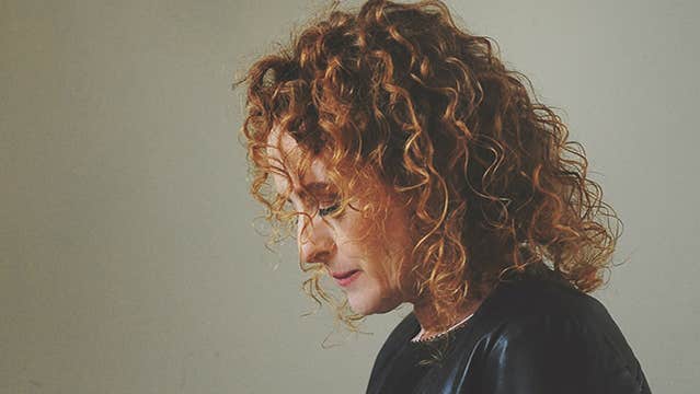 Side view of a woman with curly hair, looking downwards.
