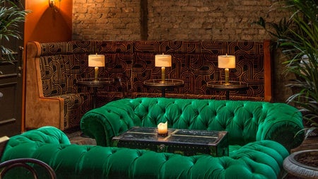 Green velvet couches in Idlewild with candlelit tables in the background