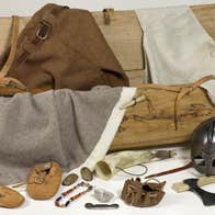 A replica Viking Chest with handmade clothes, booties and helmet with items of jewellery and axes.