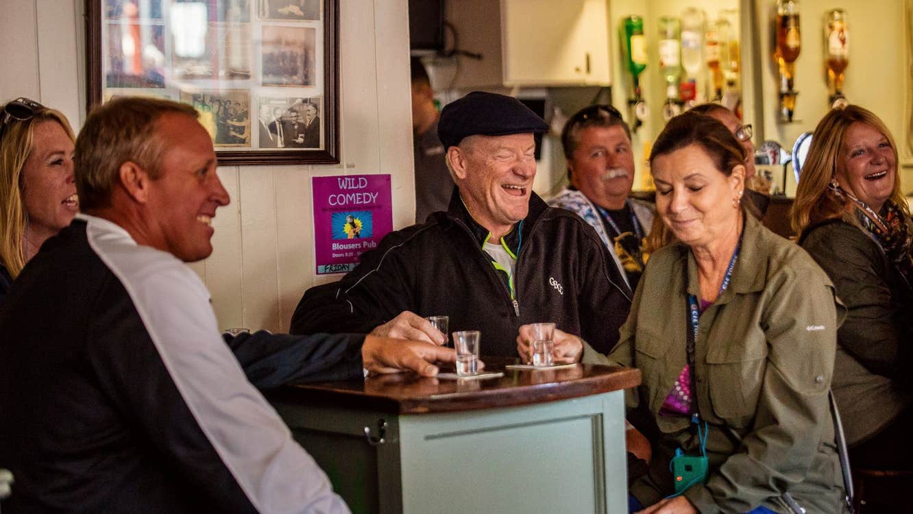 Group sitting in a pub at a tall table with empty shot glasses in front of them