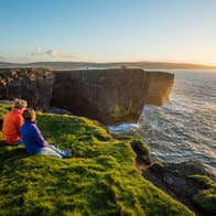 A couple watching the sunset at Downpatrick Head, Co. Mayo