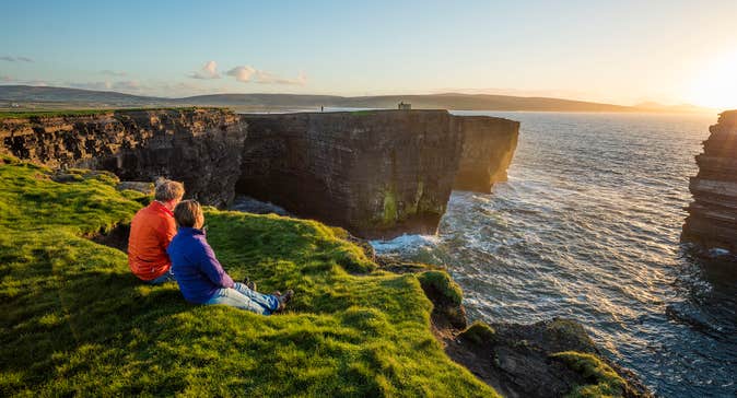 A couple watching the sunset at Downpatrick Head, Co. Mayo