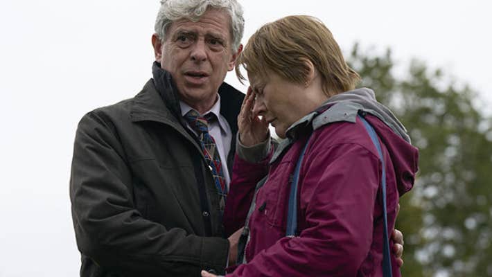A upset woman being comforted by a man outdoors.