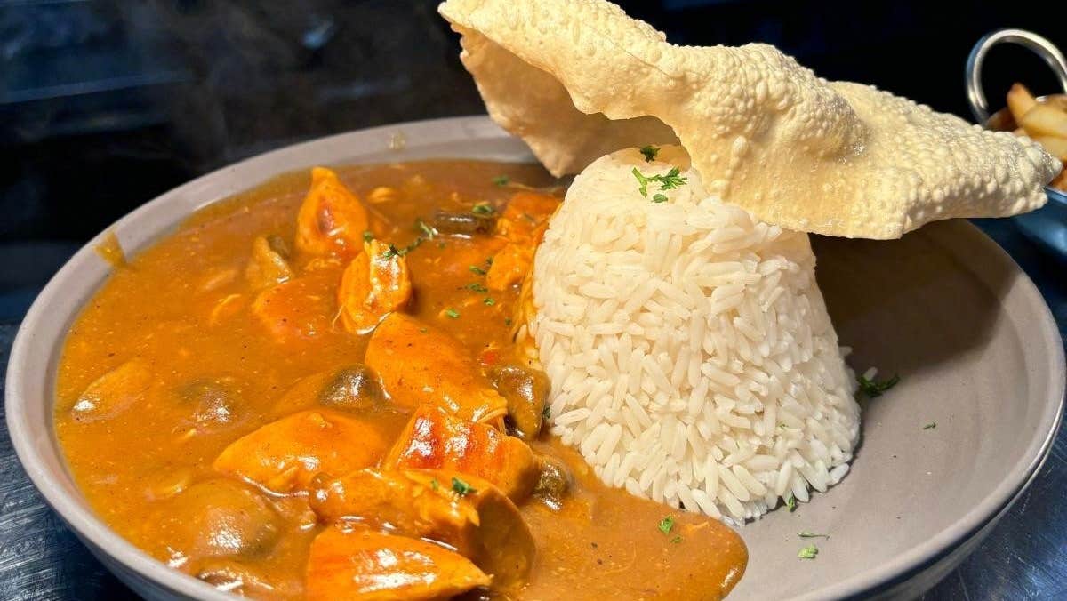 Grey bowl with red curry and rice and a poppadom in it