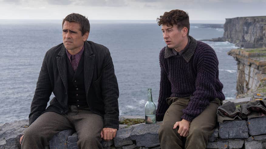 A scene from the film 'The Banshees of Inisherin', depicts actors Colin Farrell and Barry Keoghan sit on top of a stone wall with the dramatic sea cliffs of Dún Aonghasa in the background.