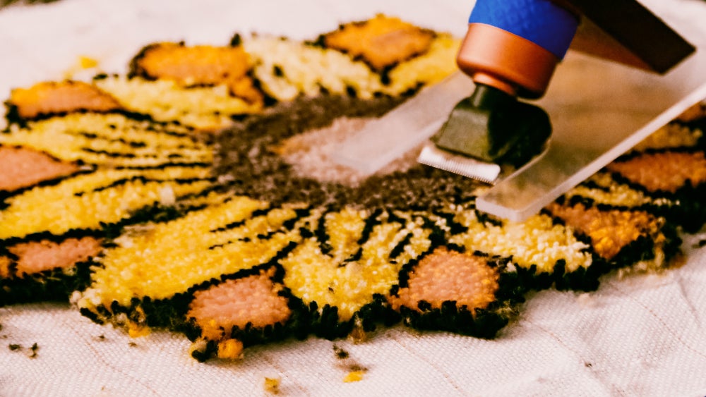 A guest shaving the details of a sunflower shaped rug.