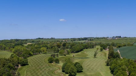 An aerial view of a golf course dotted with trees and bushes