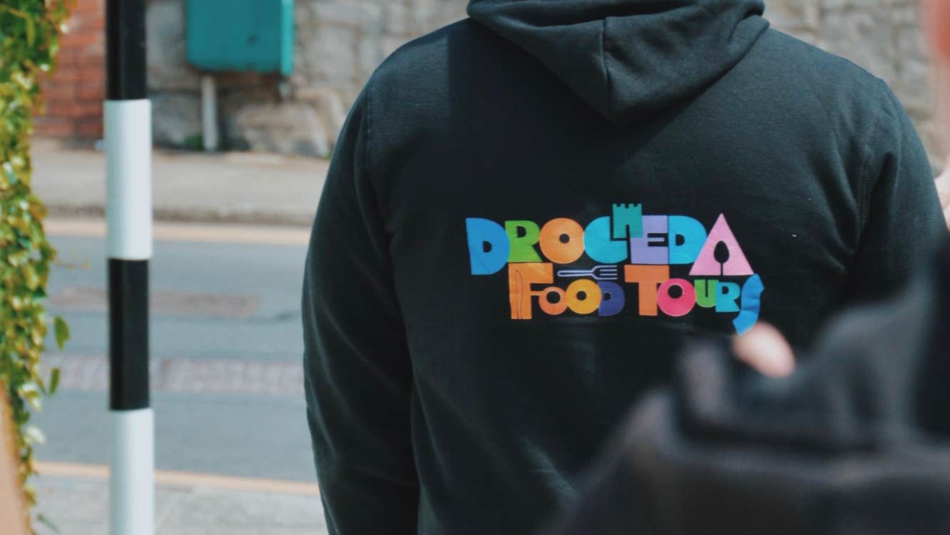 A person with their back to the camera wearing a hoodie with a Drogheda Food Tours logo