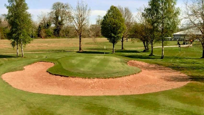 Semi circular shaped sand dune on the fairway of Slievenamon Golf Course with tress in background