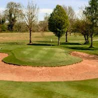 Semi circular shaped sand dune on the fairway of Slievenamon Golf Course with tress in background
