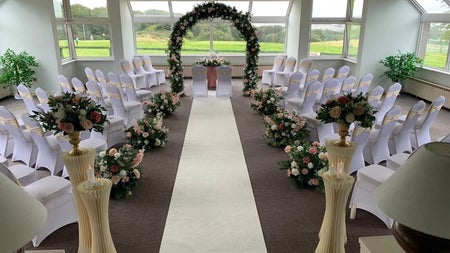 Function room set up for a wedding with chairs and flowers