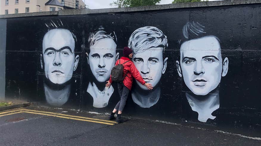 Woman hugging a mural of Irish boy band Westlife in Sligo.