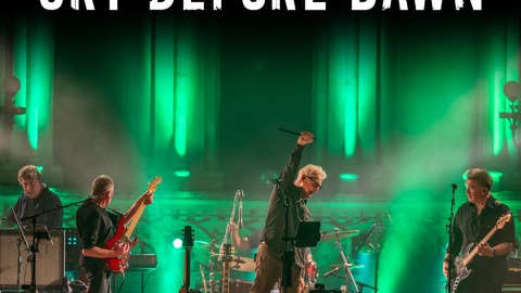 A band performing in stage with green lighting