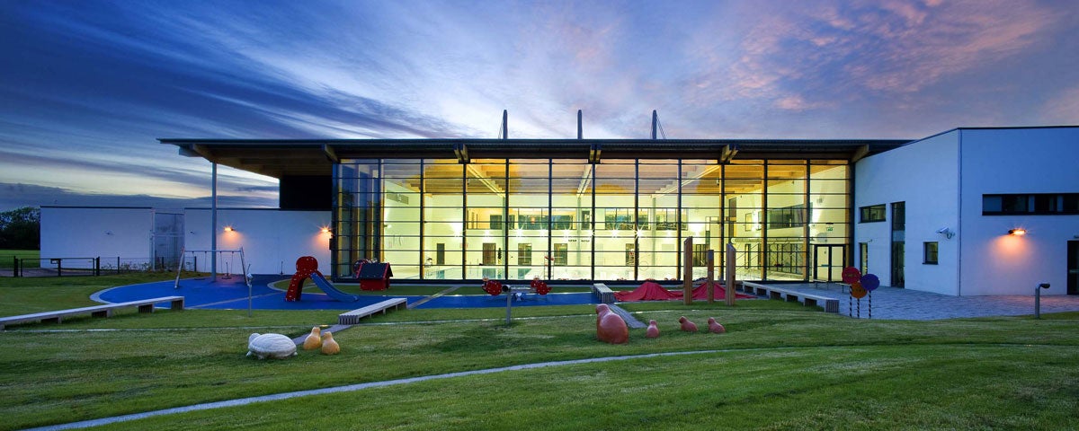 Exterior of Clondalkin Leisure Centre in the evening with the glass front of building lit up