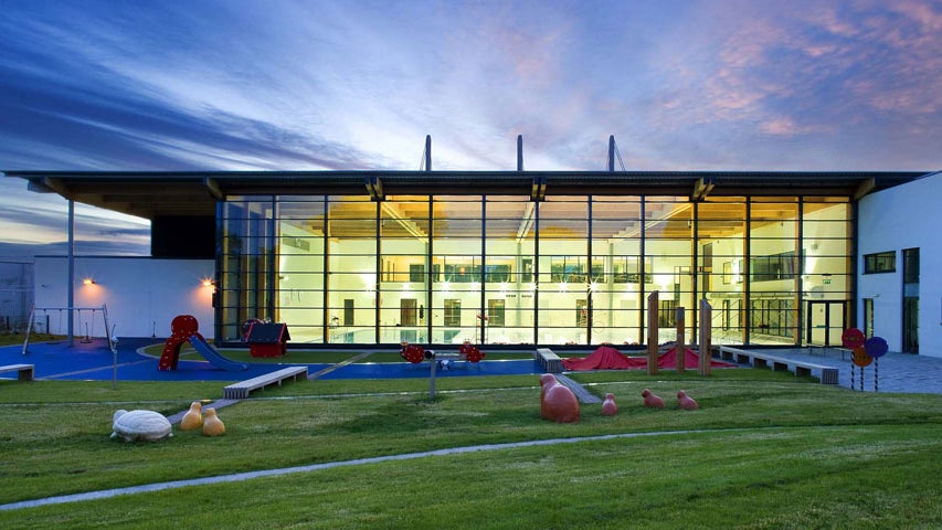 Exterior of Clondalkin Leisure Centre in the evening with the glass front of building lit up