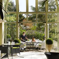 Garden view restaurant with a staff member setting a table beside large open windows