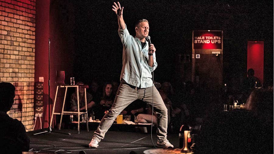 A comedian standing on stage in mid performance