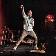 A comedian standing on stage in mid performance