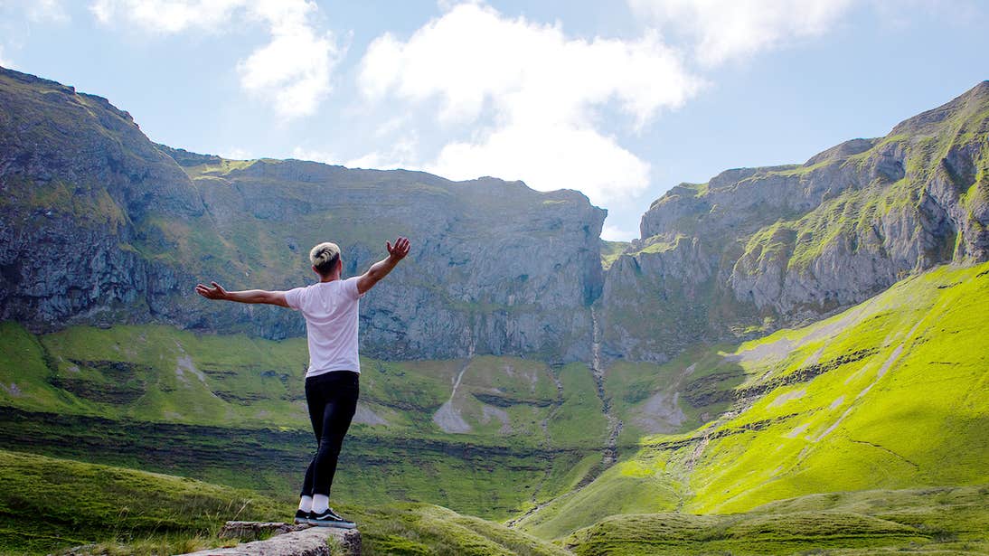 A person spreading their arms for a photo standing in the unique landscape of the Gleniff Horseshoe Drive, Sligo