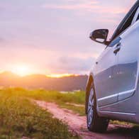 Small car on a country lane facing the setting sun