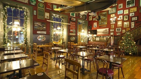 The interior of a restaurant with tables and chairs decorated for Christmas