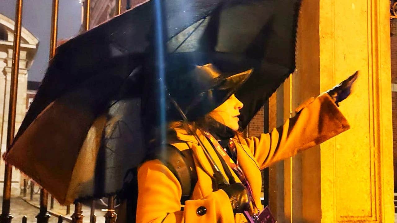 A woman dressed dramatically with an umbrella giving a tour