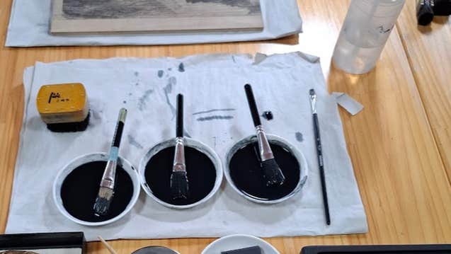 Japanese Water-Based Woodblock Printing (Mokuhanga), art materials for printing laid out on a table including pots of dark ink & brushes