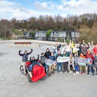 A group of people posing with trishaws and signs promoting cycling