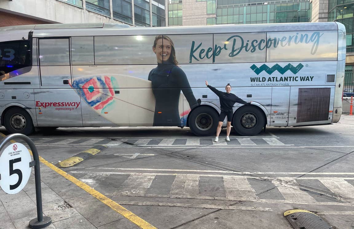 Woman posing in front of an Expressway Keep Discovering bus.