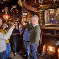 Four people tasting and toasting each other with whiskey by a pub fireside