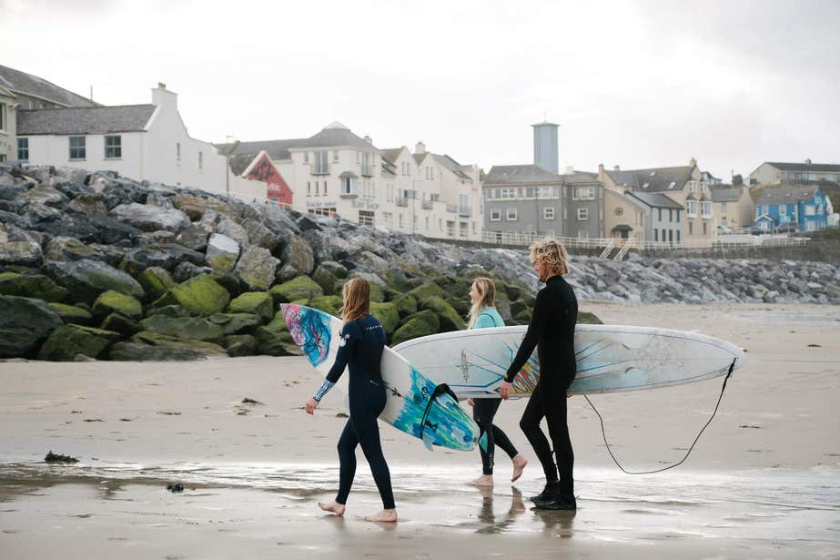 Surfers walking back to town on Lahinch.