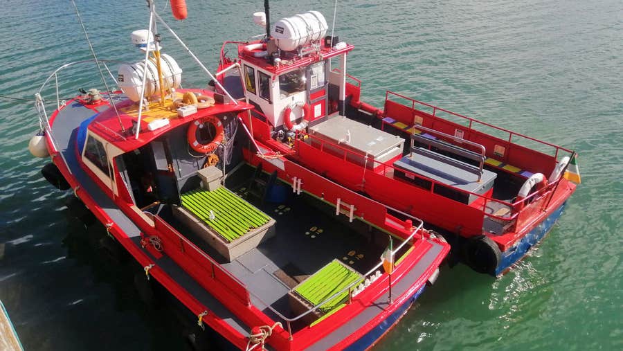 Two small passenger ferries orange in colour tied up at pier