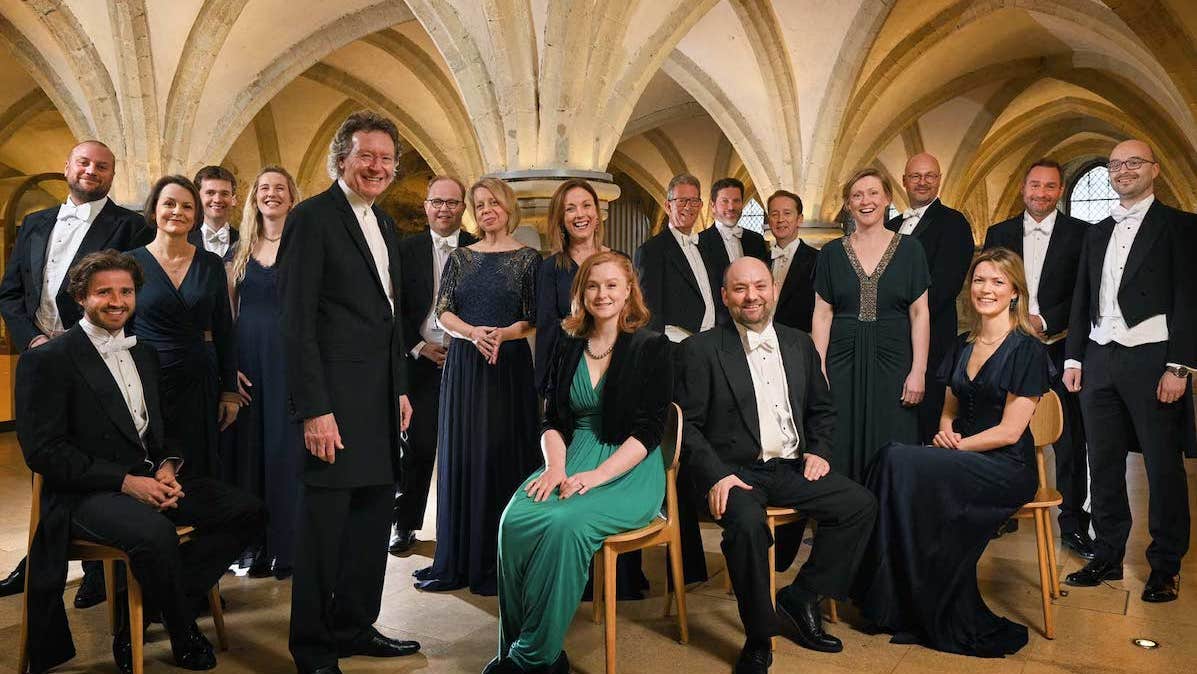 The Sixteen - A Choral Pilgrimage, a group of people in evening dress, some seated, under a low stone arched ceiling