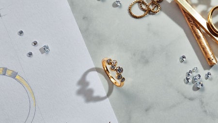 Image of six stone gold ring and a pencil sketch with loose diamonds around.