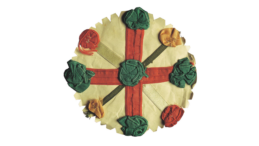 Old circular cloth badge in off white, green and red